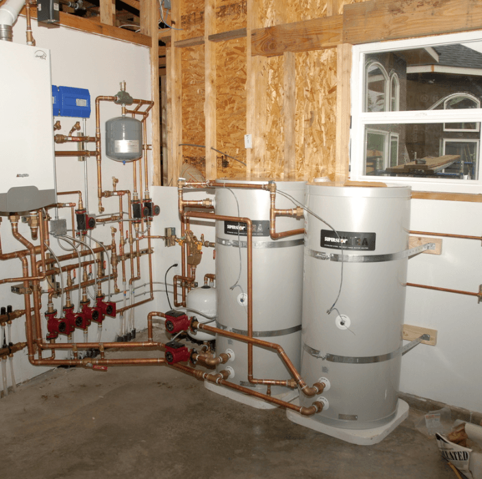 A finished mechanical room with a tall water heater, organized copper manifold piping and tidy radiant-heat circulator pumps.