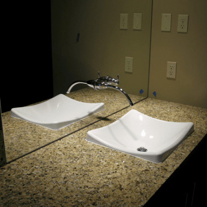 Two white vessel sinks on a granite countertop with chrome fixtures in a finished bathroom.